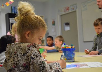child drawing with a marker with other students