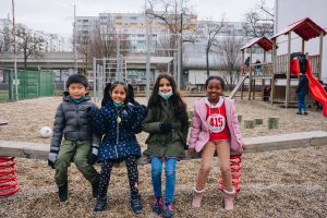 four children in the playground smiling at the camera