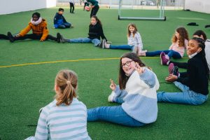 students kids sitting in a circle on field together playing